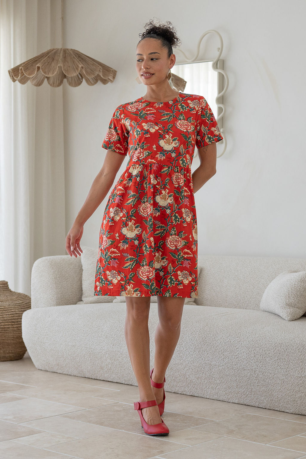 Woman wearing a above knee length floral cotton dress with short sleeves, pockets and round neckline