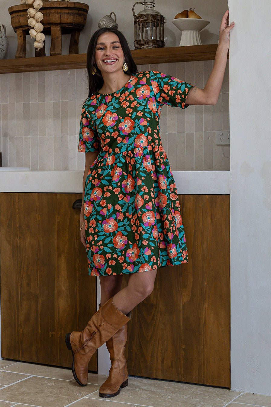 Woman wearing a 100% cotton relaxed fit dress with round neckline and short sleeves in olive green based floral print.
