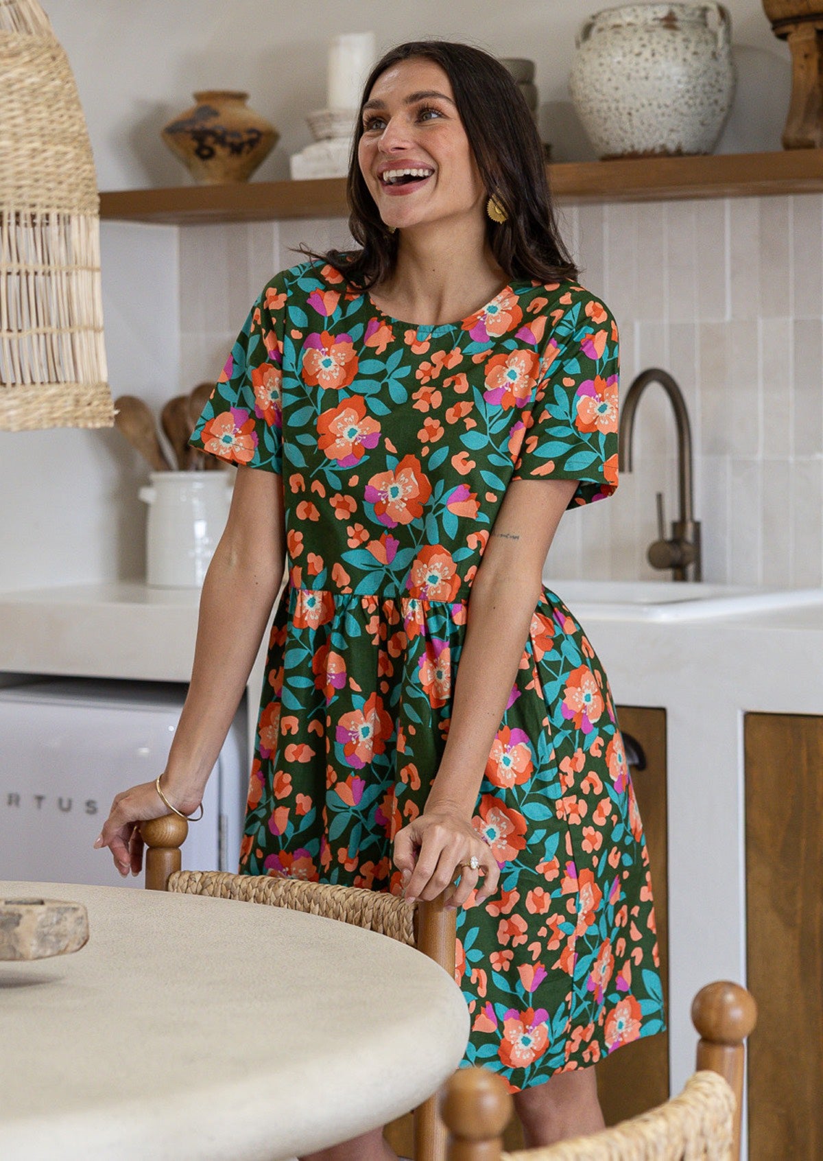 Woman wearing a 100% cotton olive green based floral relaxed fit dress with round neckline and short sleeves.
