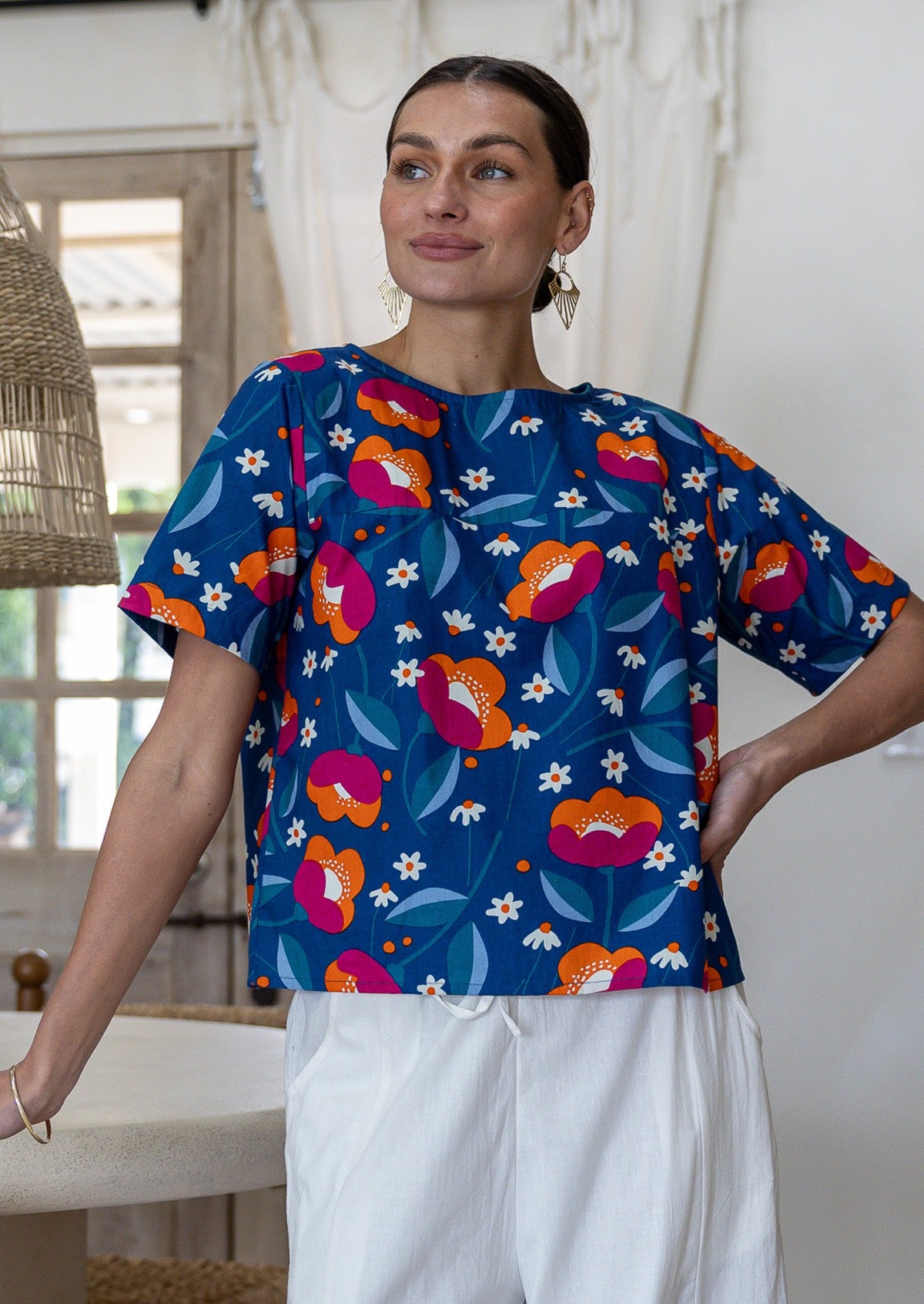 Woman wearing a royal blue based floral printed relaxed fit cotton top with short sleeves and high neckline