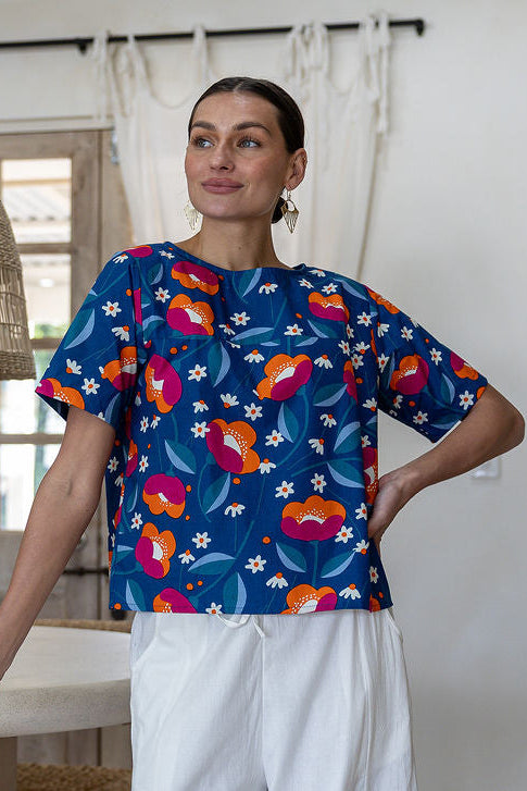 Woman wearing a royal blue based printed cotton top and white pants.