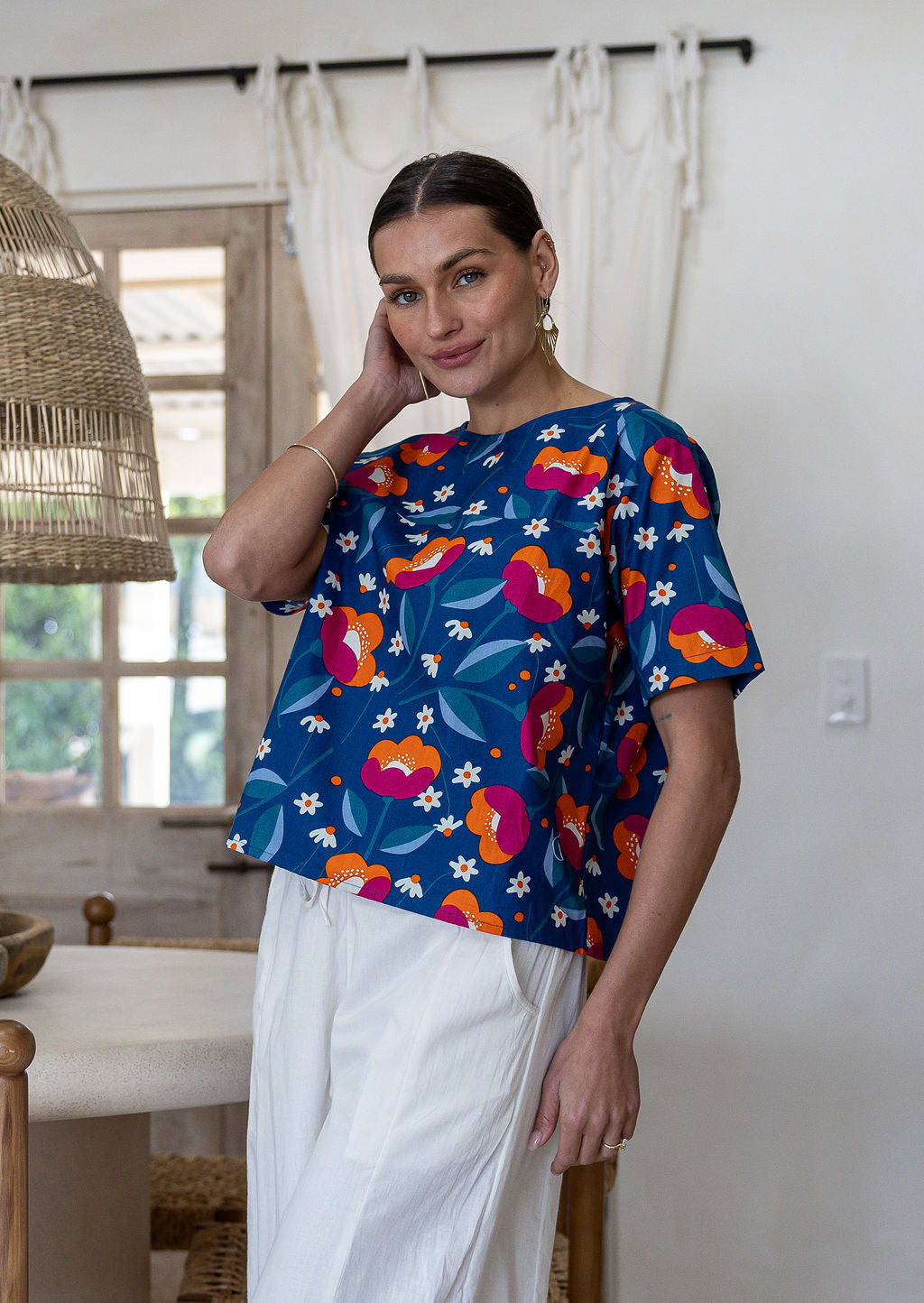 Woman wearing a royal blue based floral printed cotton short sleeved top and white plain pants.