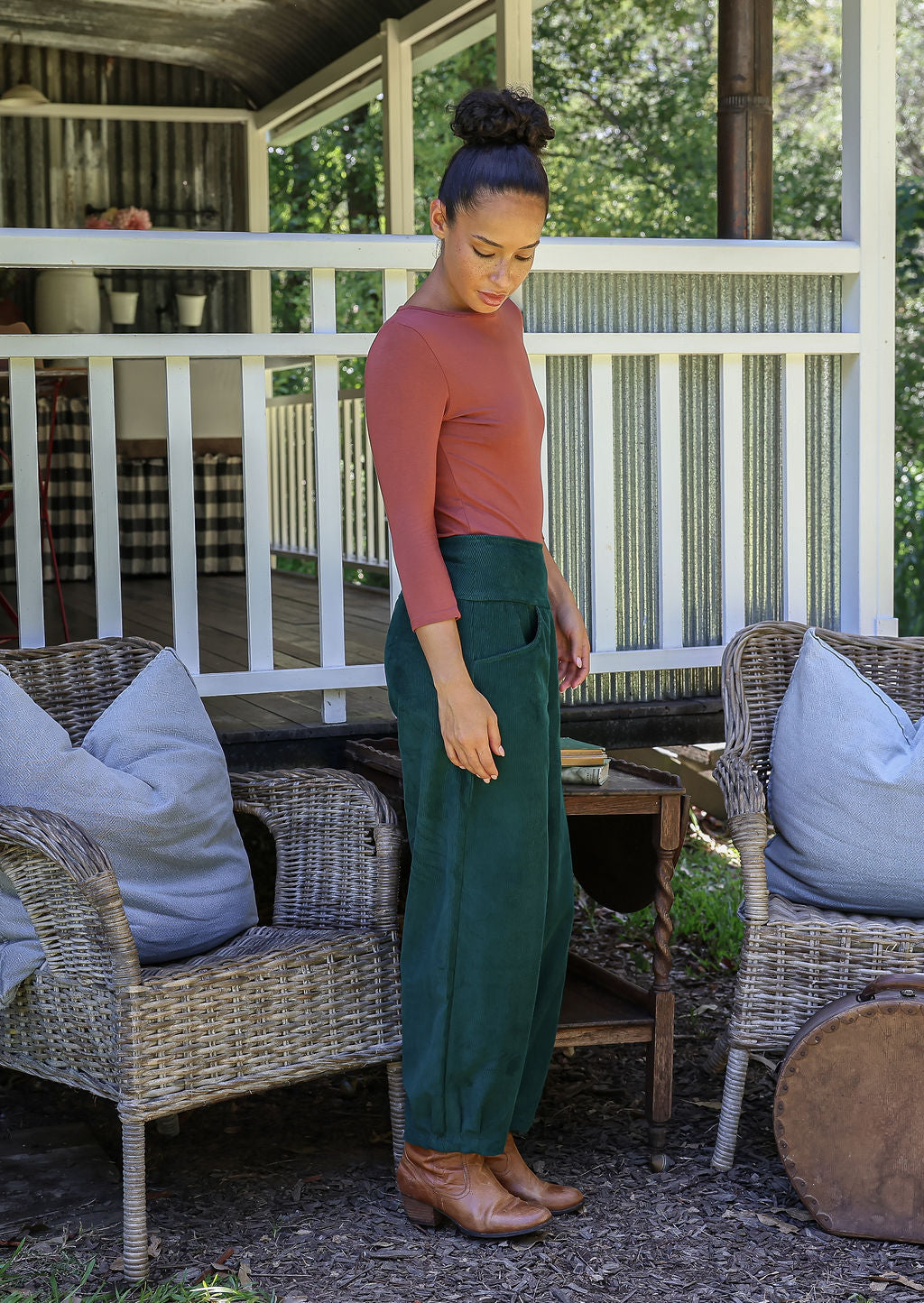 Model standing sideways wears corduroy wide leg pants with side zipper, pockets and small pleats at ankles.