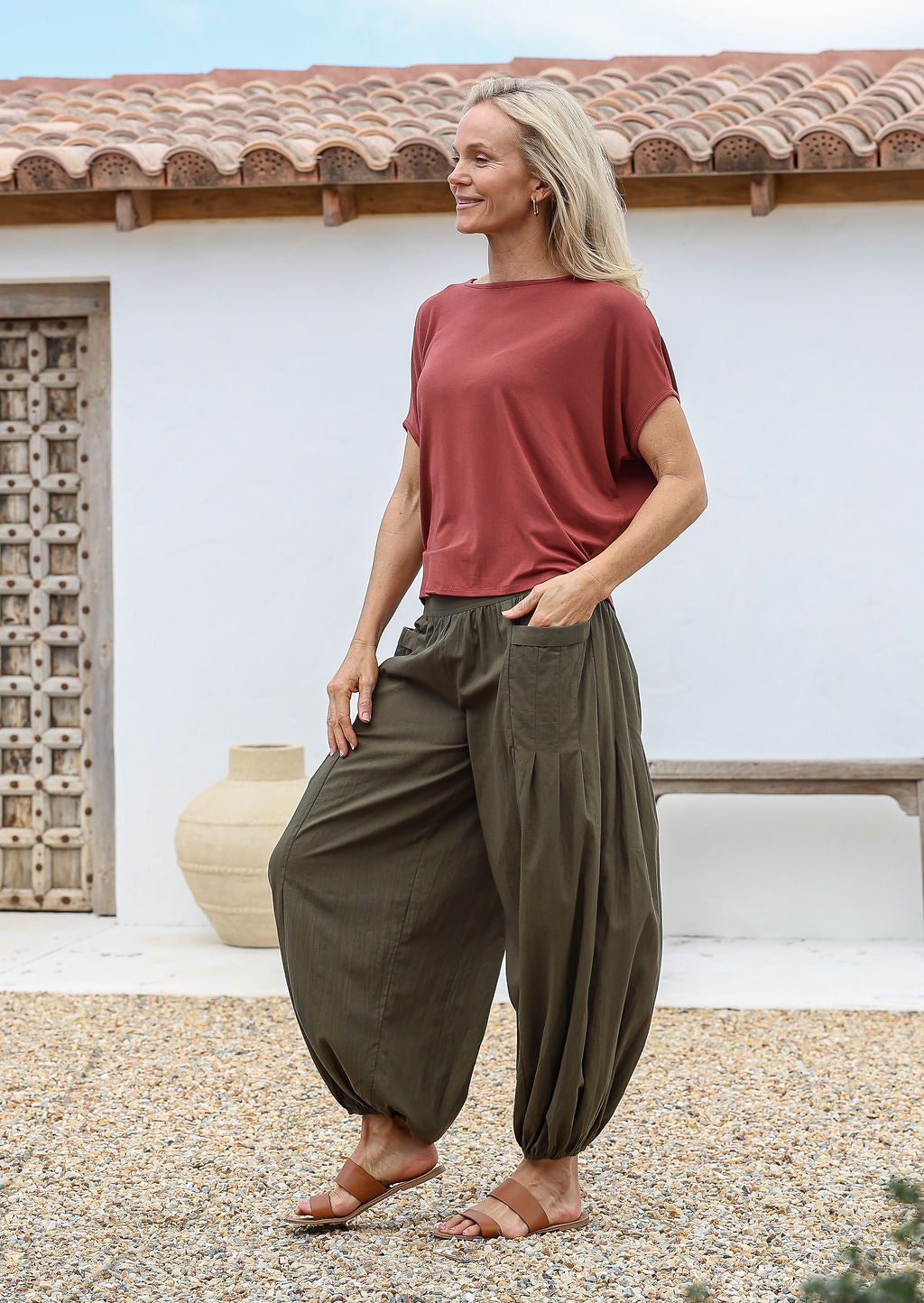 Woman wears terracotta rayon top with aladdin style cotton harem pants featuring deep pockets and elasticated ankles and waist.
