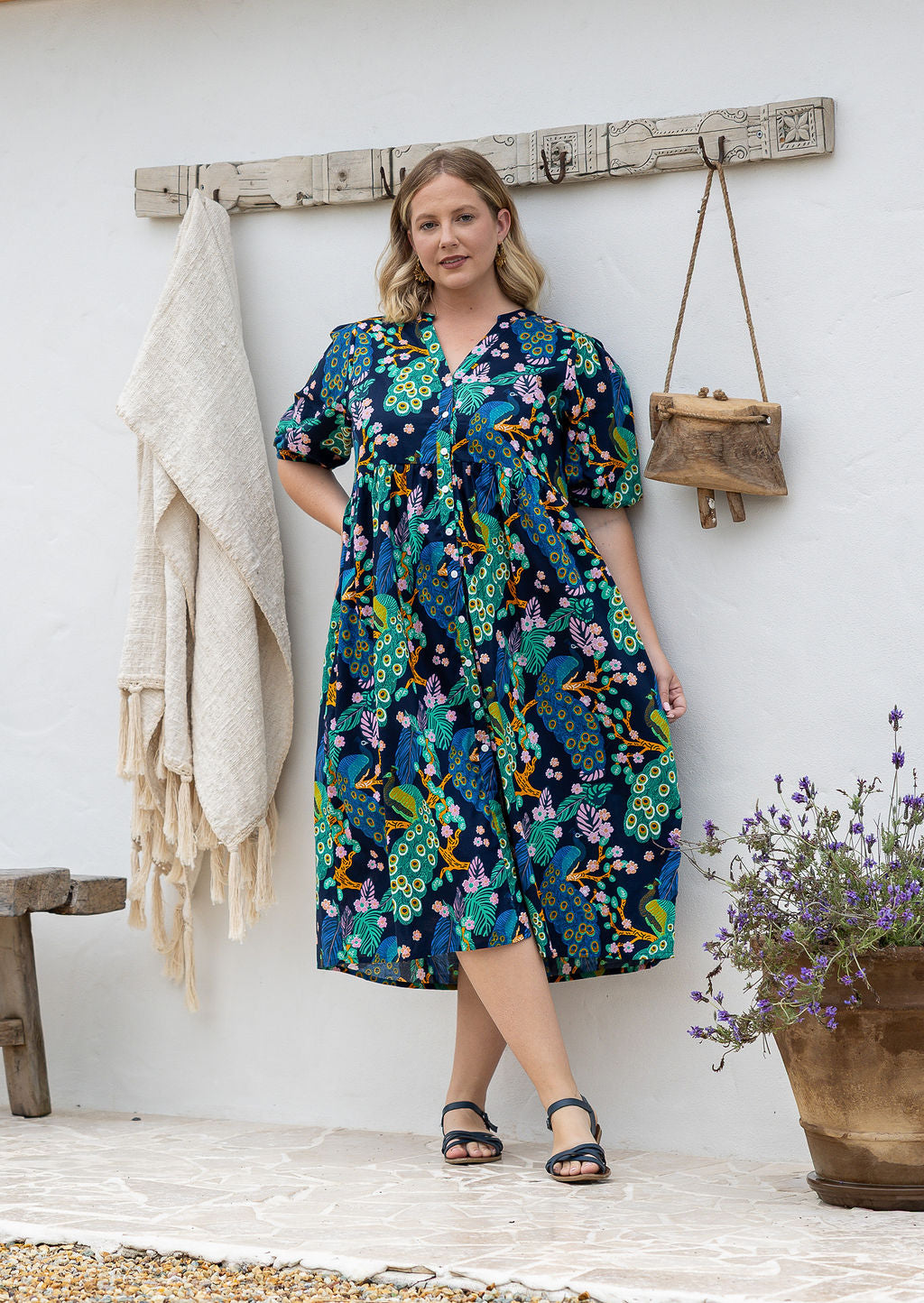Woman wearing navy based colourful floral cotton button through dress with hidden side pocket