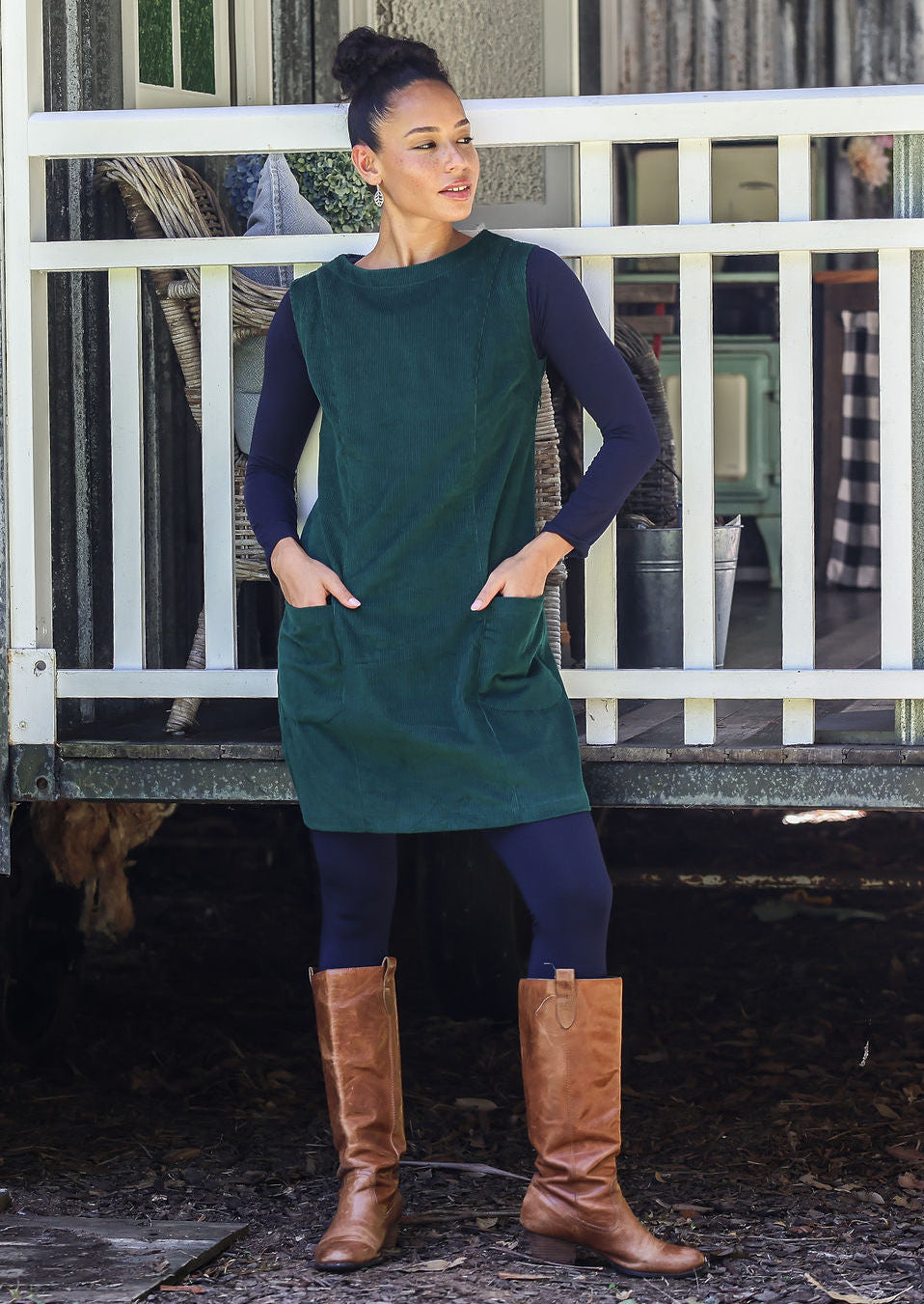 Woman wearing cotton corduroy tunic in dark green with boat neck and front pockets
