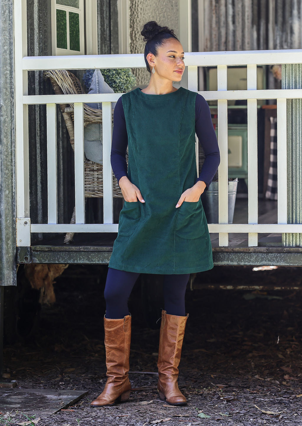 Woman wearing cotton corduroy tunic in dark green with boat neck with hand in pocket
