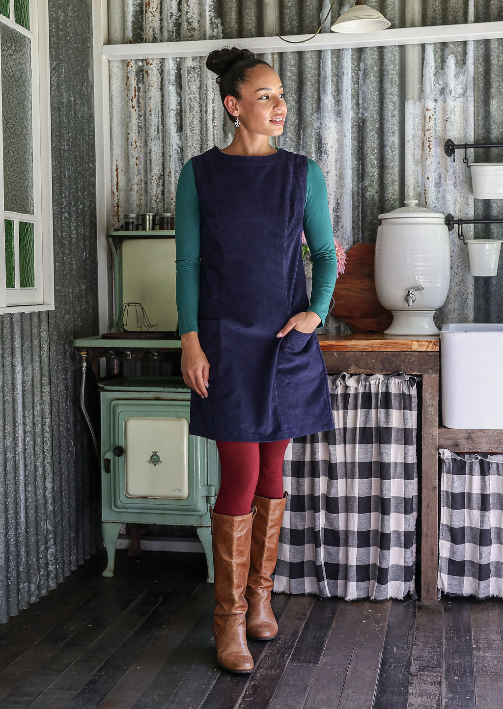Woman wearing a navy tunic over a leggings and a top in a rustic setting.
