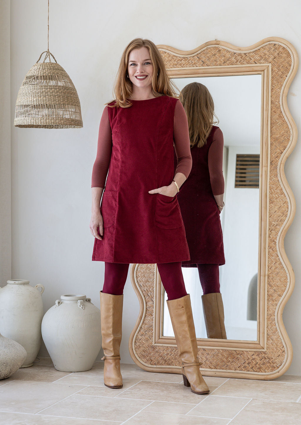 Woman wearing cotton corduroy tunic in cabernet with boat neck with one hand in pocket
