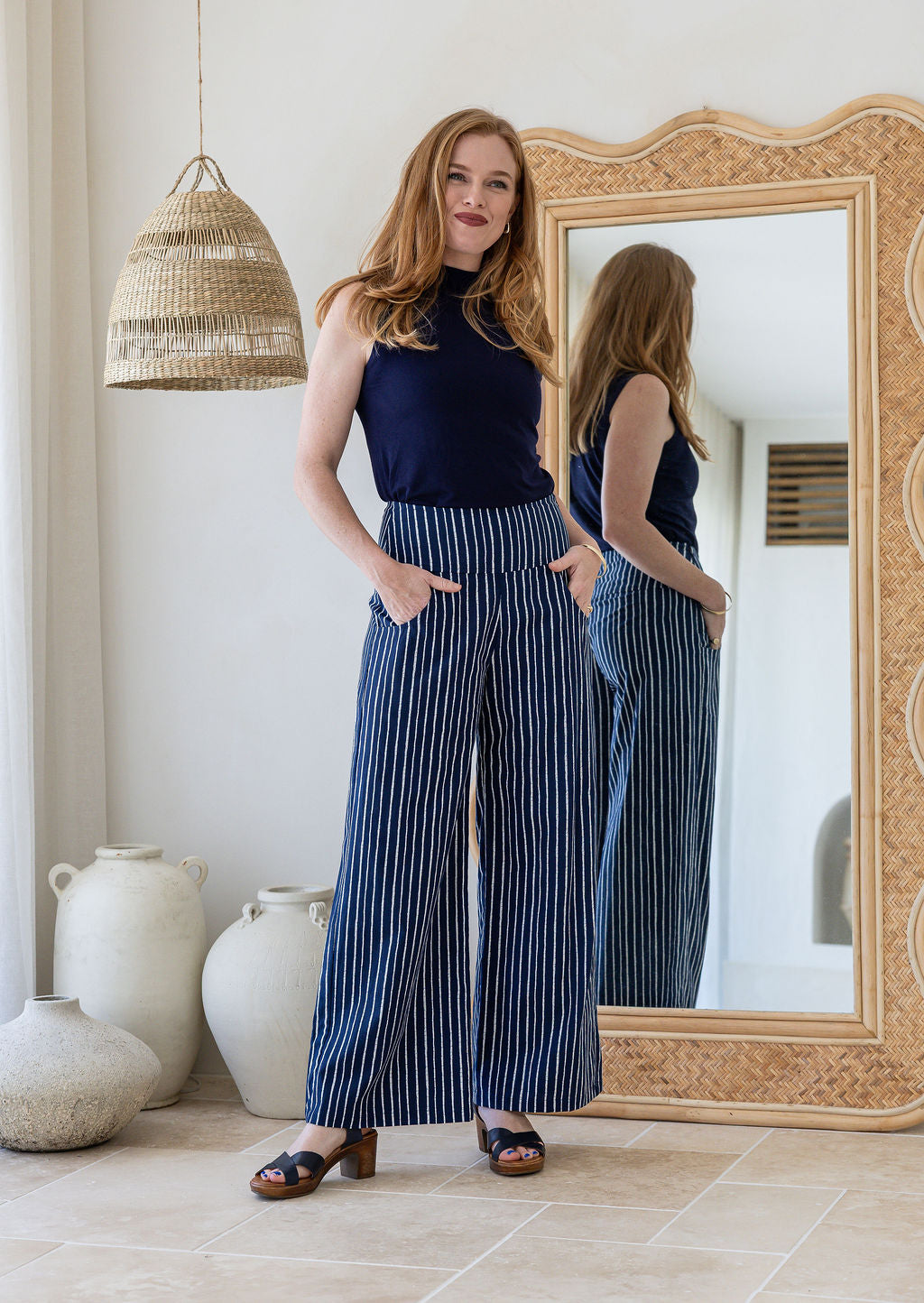 Model wearing a wide leg 100% cotton pant with navy based white striped print standing against a mirror