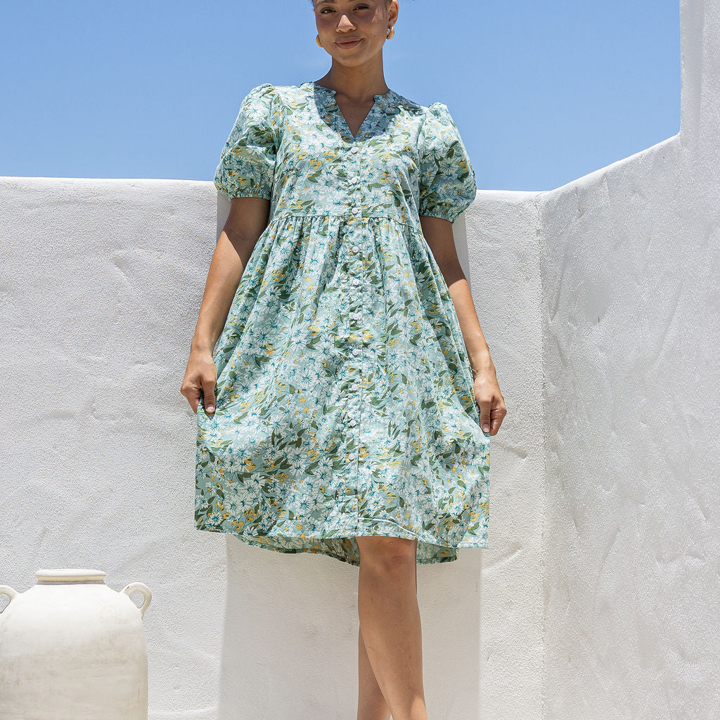 Woman wearing a knee length relaxed fit button through 100% cotton dress with elbow length sleeves