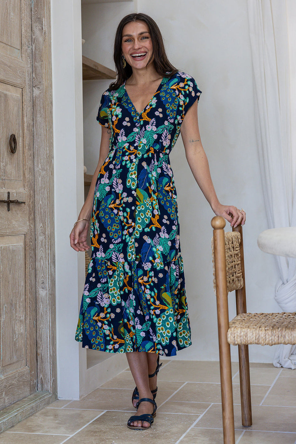Woman standing in midi length rayon dress button through dress with V-neckline and elasticated waistband