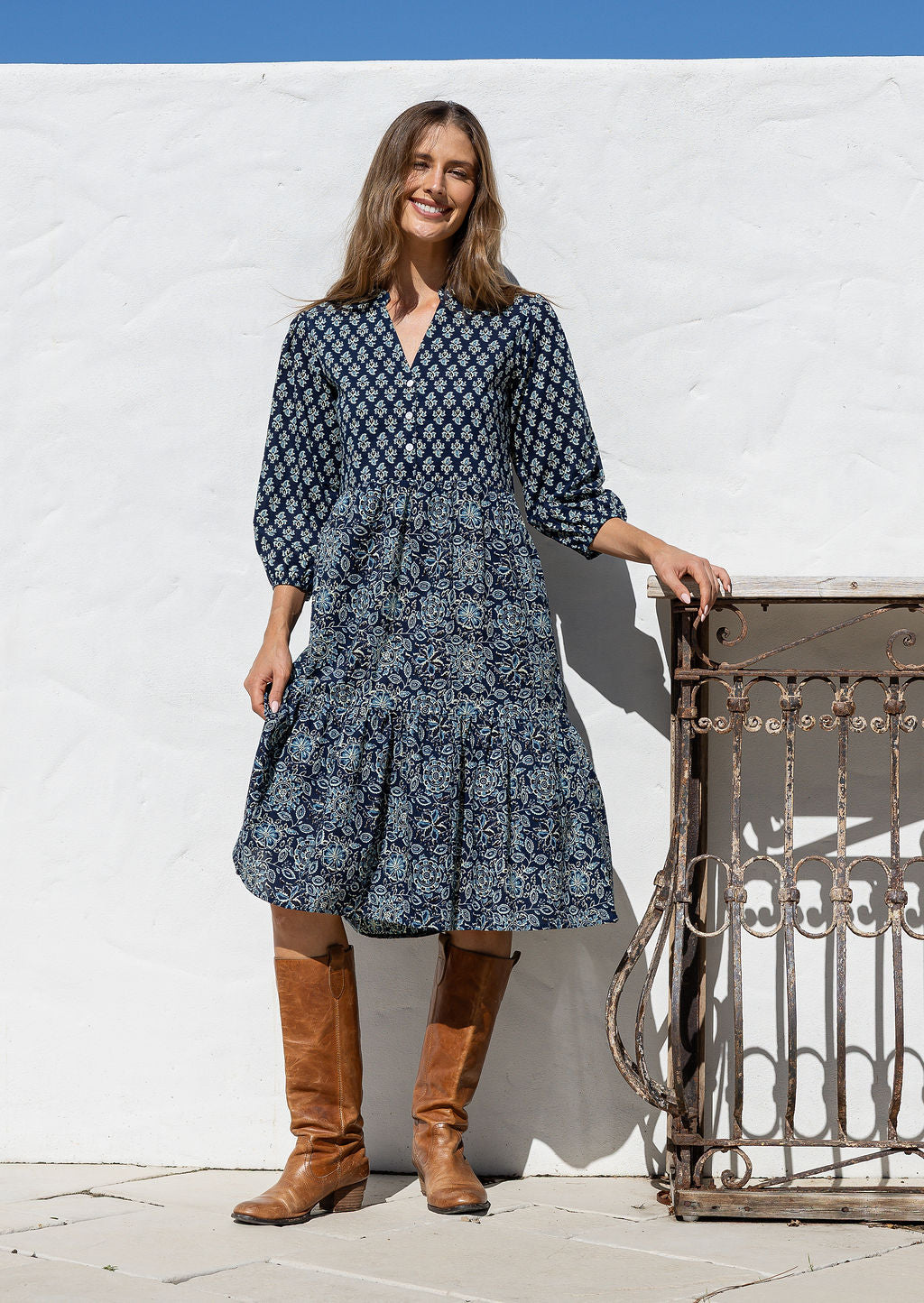 Woman poses in cotton tiered over the knee dress with 3/4 sleeves, buttoned bodice and V-neckline