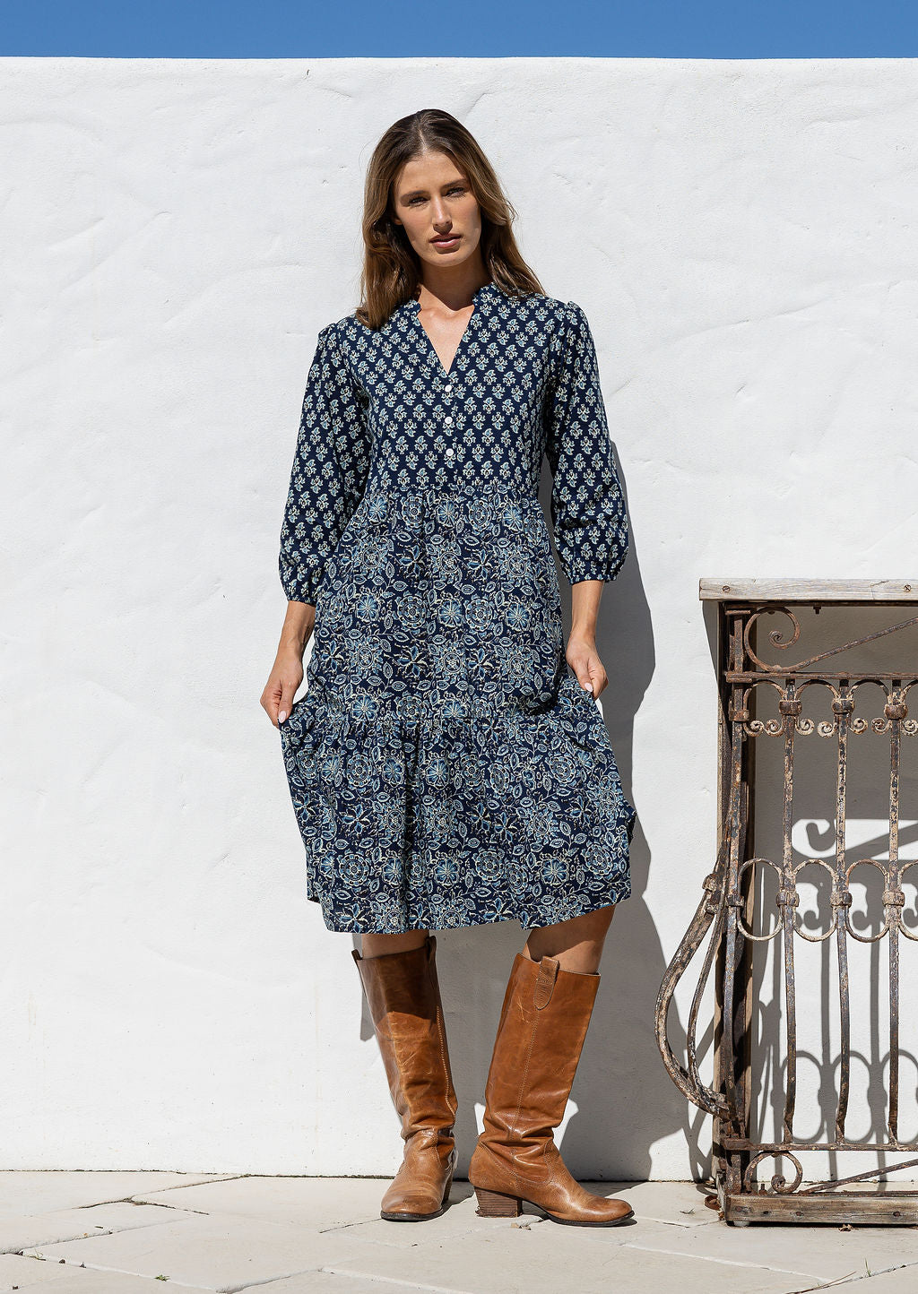 Model stands on in cotton over the knee length relaxed fit dress with 3/4 sleeves, paired with brown boots.