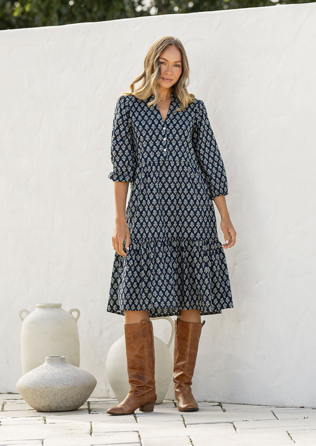 Woman poses in cotton tiered over the knee dress with 3/4 sleeves, buttoned bodice and V-neckline