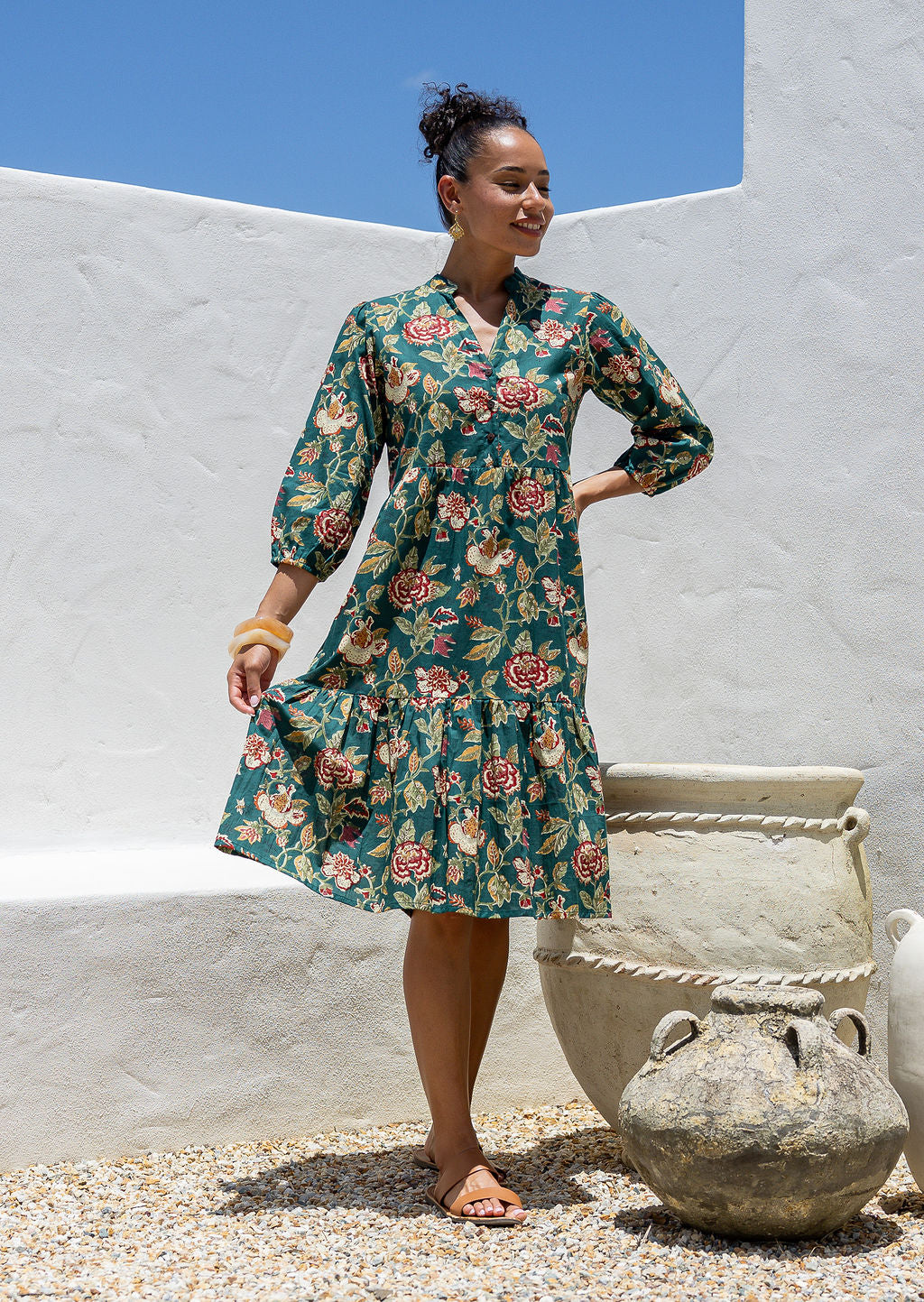 Woman flaunting cotton tiered dress in green floral print, with 3/4 sleeves, buttoned bodice and V-neckline