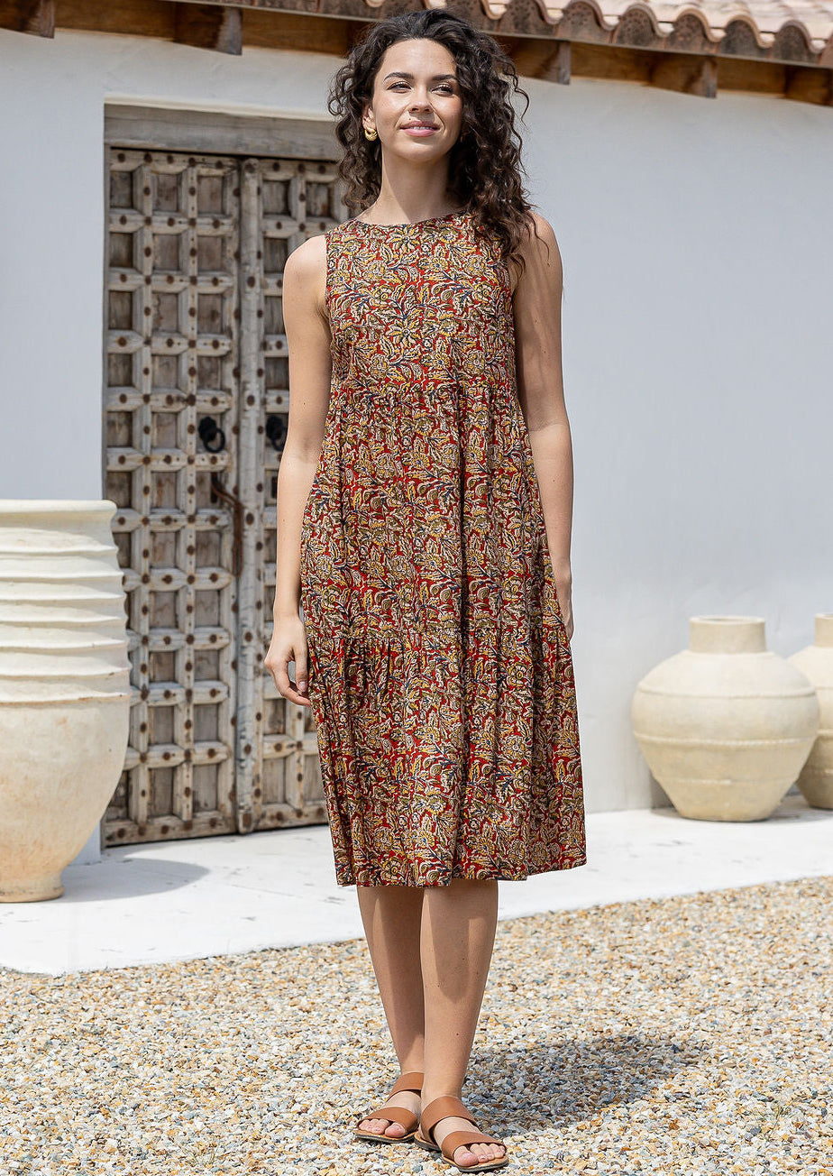 Woman stands in Indian floral cotton print sleeveless midi length dress with high round neckline