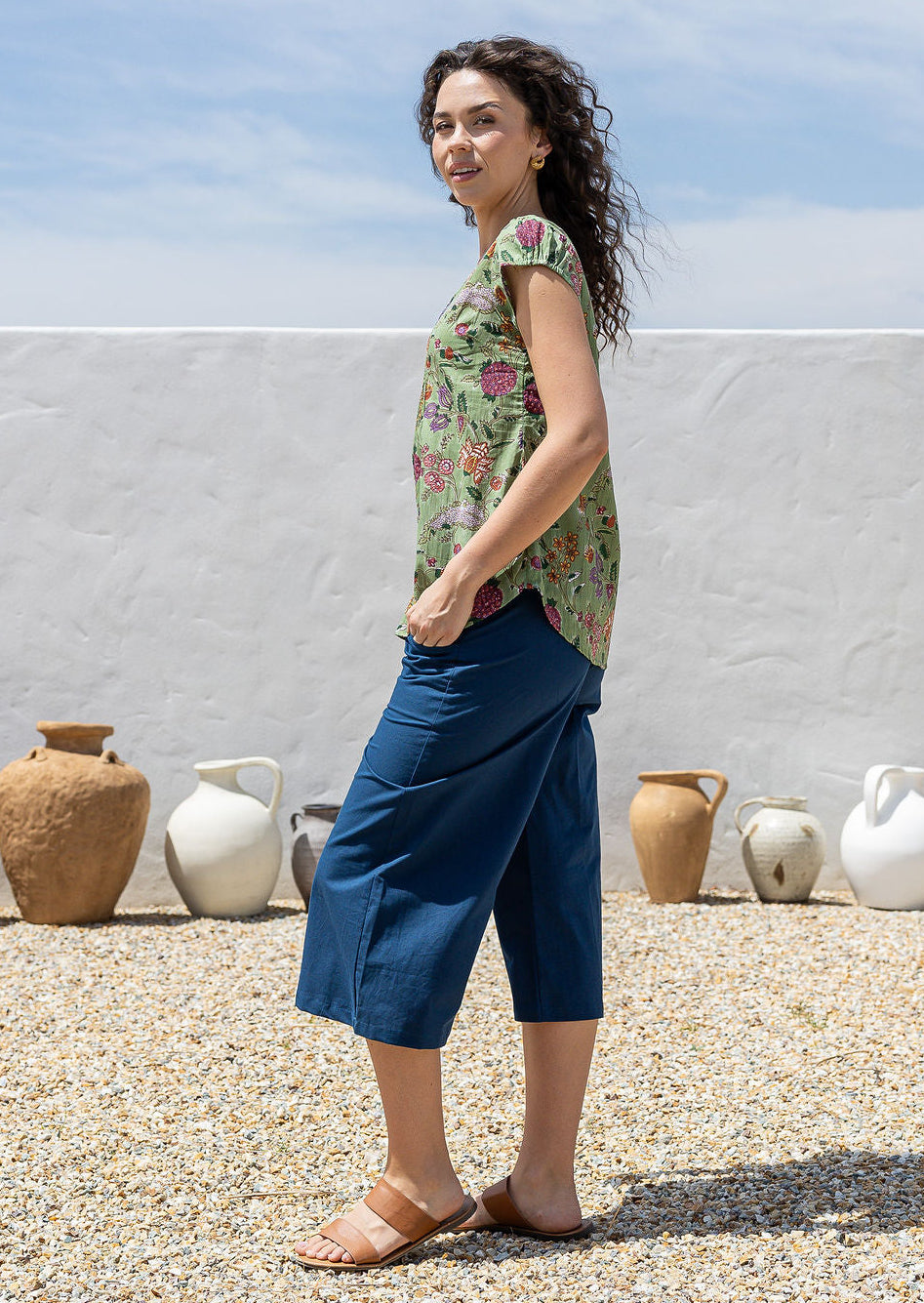 Woman wearing a moss green based multi-coloured folk art style florals 100% cotton top