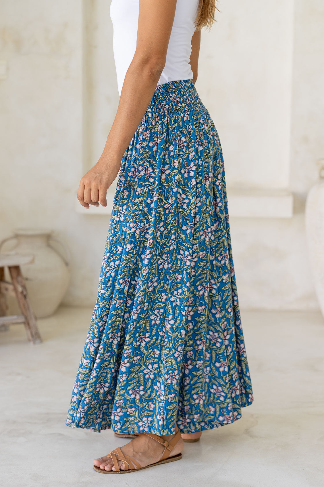 Close up of a model wearing a blue based flowy, wide legged pants with smocked elastic waistband.