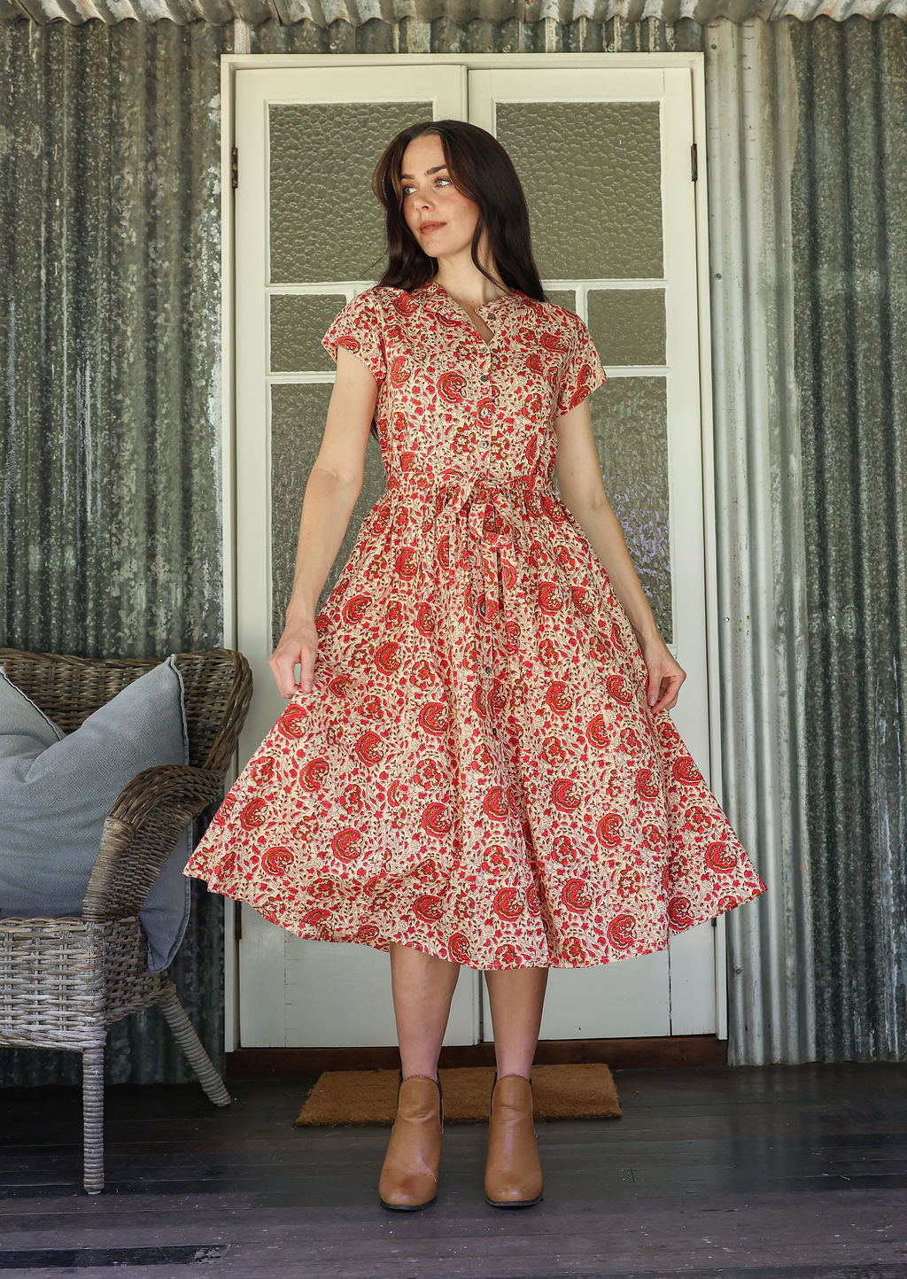 Woman wears 100% cotton button through midi length dress with short sleeves and pockets in floral print on a gentle cream base.