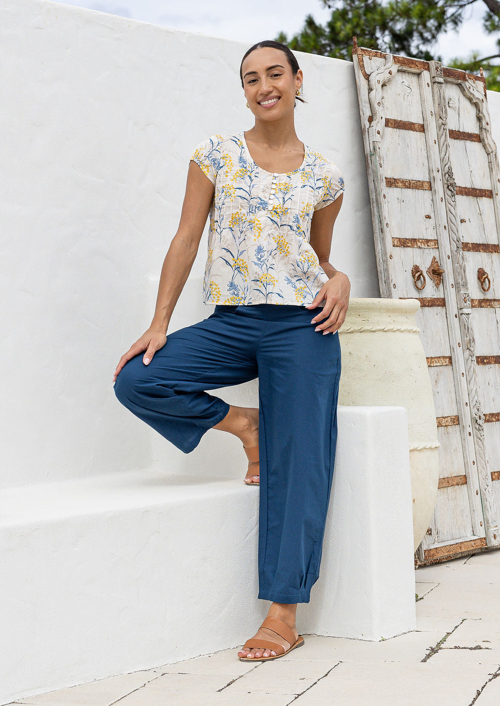 Woman wearing a neutral based floral print cotton top with blue pants.