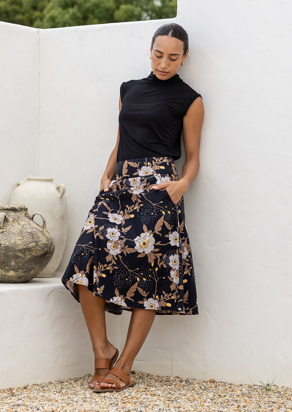 Woman is posing with both hand in pockets wearing a 100% cotton black a-line skirt.