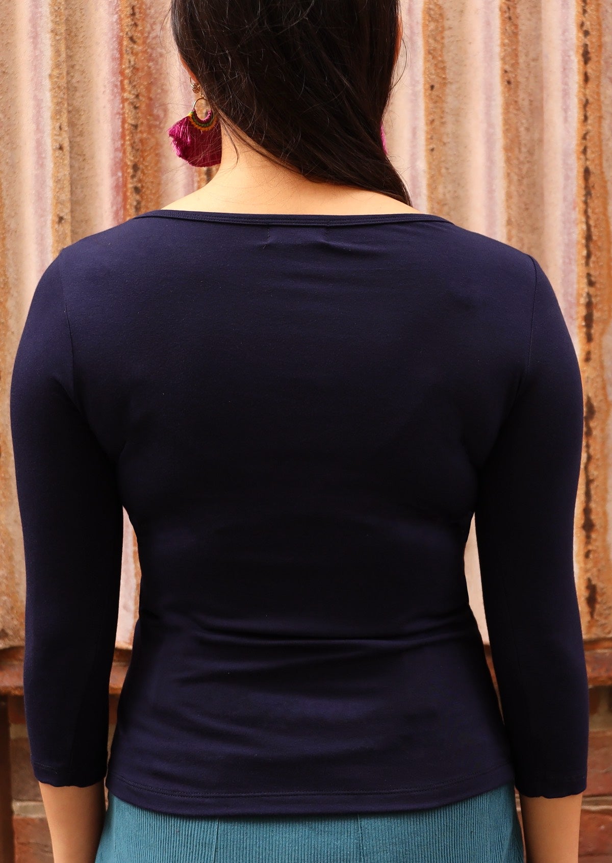 Back view of a woman wearing a rayon boat neck navy blue 3/4 sleeve top.