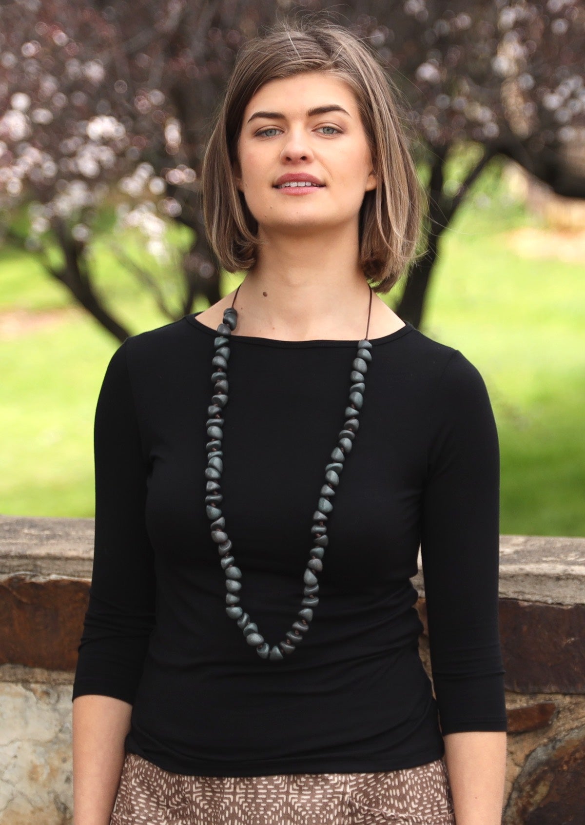 Woman with brown hair wearing a rayon boat neck black 3/4 sleeve top