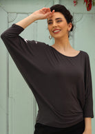 Woman with dark hair wearing a 3/4 sleeve rayon batwing round neckline dark grey top.