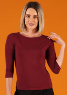 Woman with blonde hair wearing a rayon boat neck maroon 3/4 sleeve top.