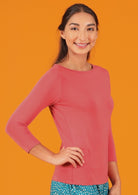 Woman with dark hair wearing a rayon boat neck pink 3/4 sleeve top.