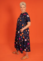 Short sleeve cotton pocket dress with tiers in colorful orange, pink, plum and blue splotchy print.