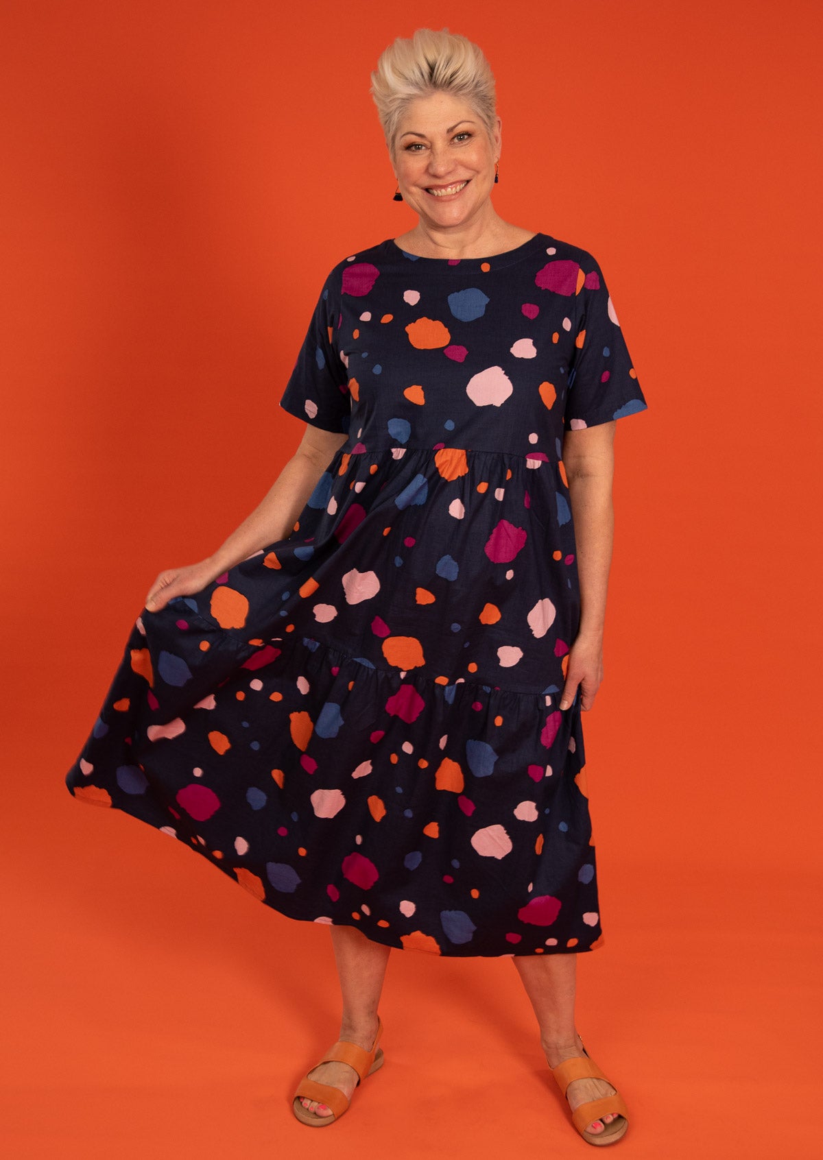 Grey haired model wears three tiered 100% printed cotton dress with pockets