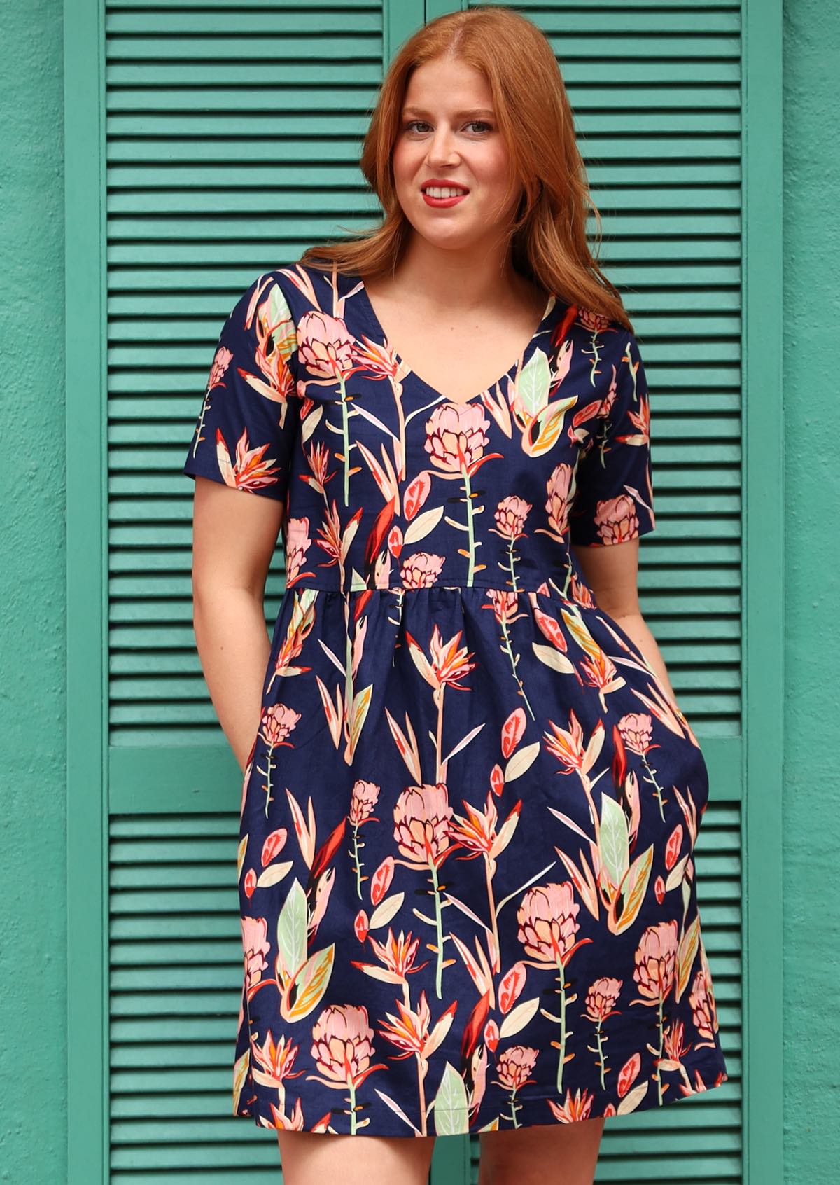 Woman in Harlow Dress Bold Botanic Printed Cotton Dress V-neckline short sleeve gathered waistline above the knee skirt and pockets