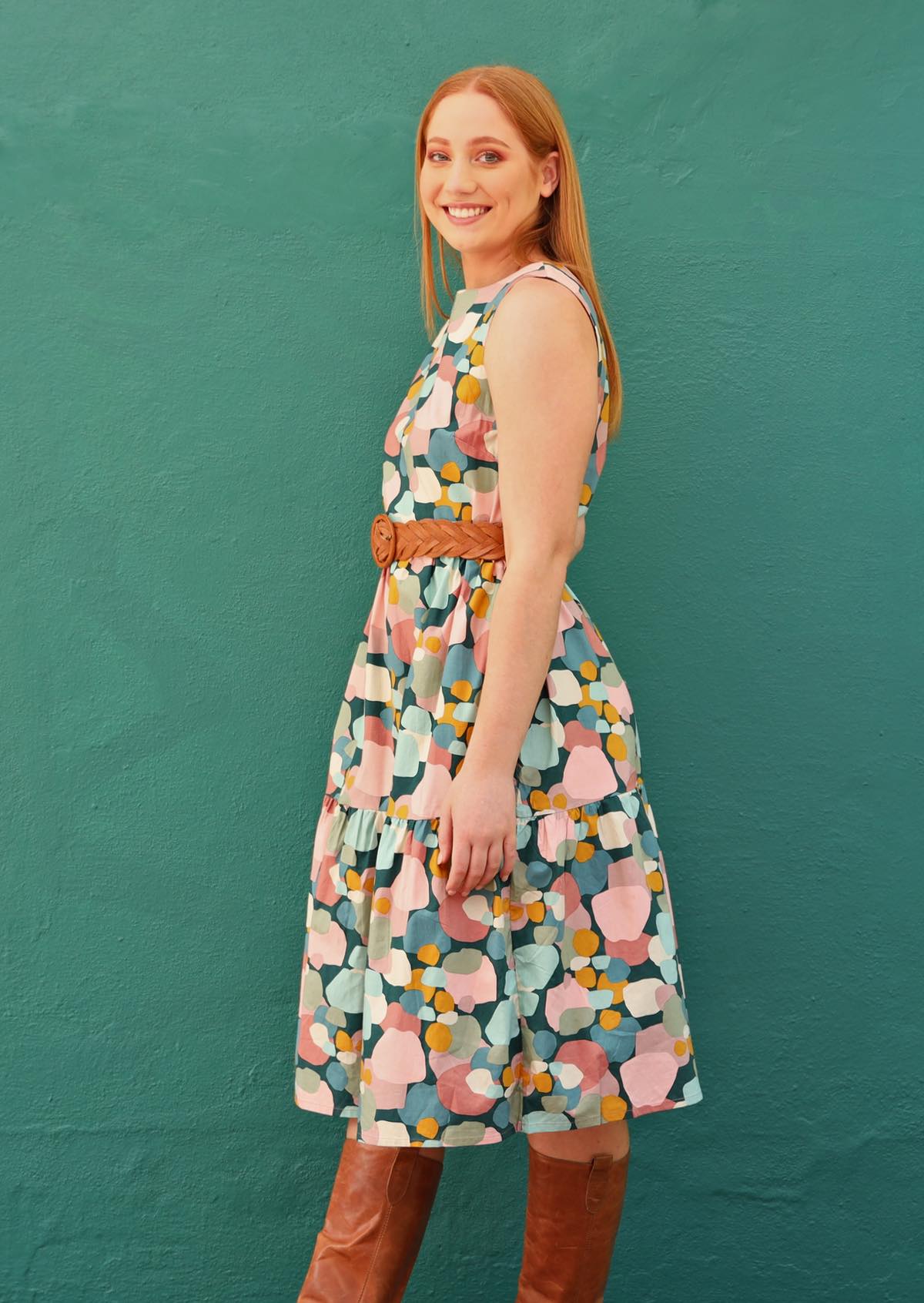 Model wearing sleeveless, colorful print cotton dress with belt.