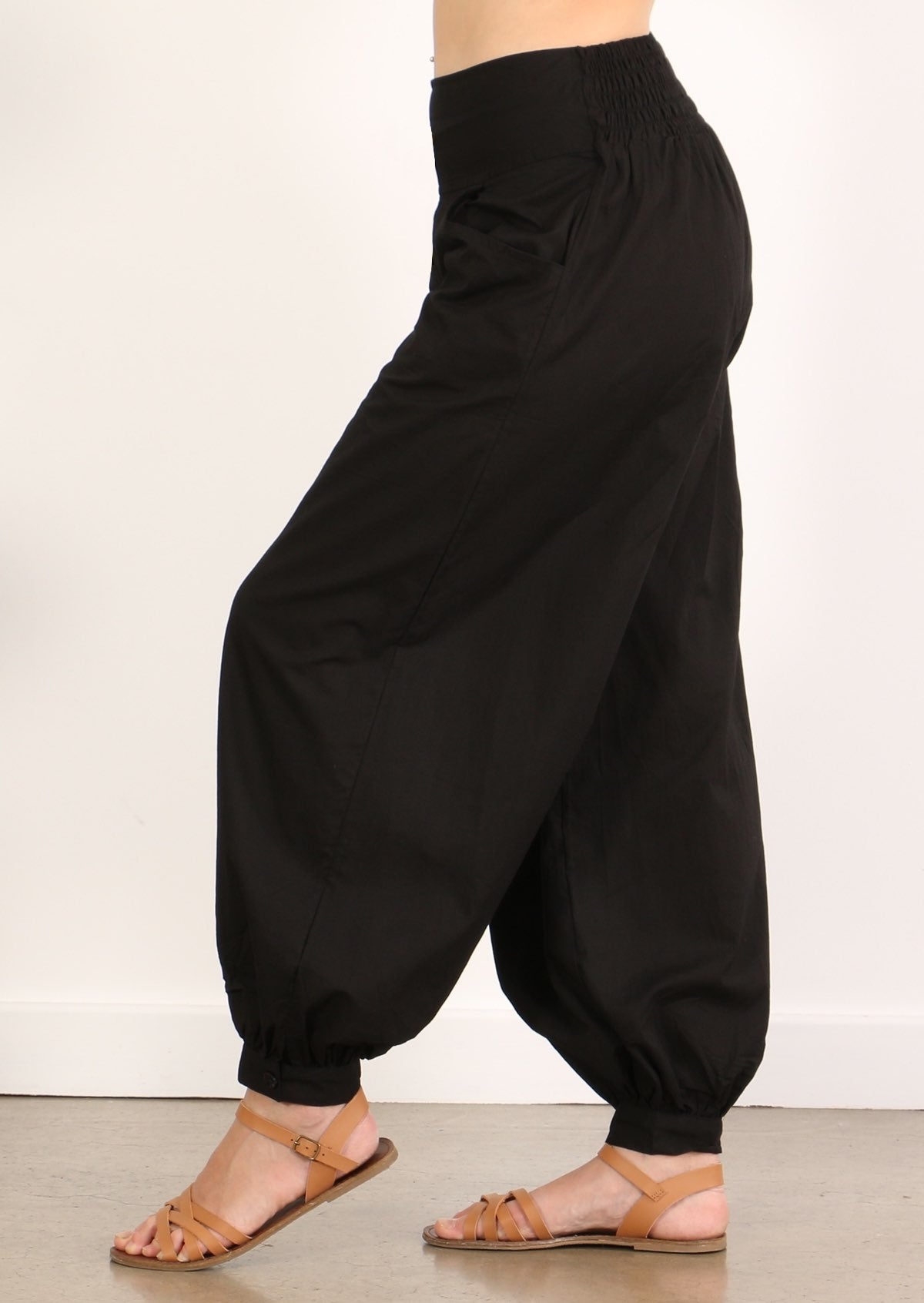 Side view of simple cotton women's pants in black with ankle cuff and pockets