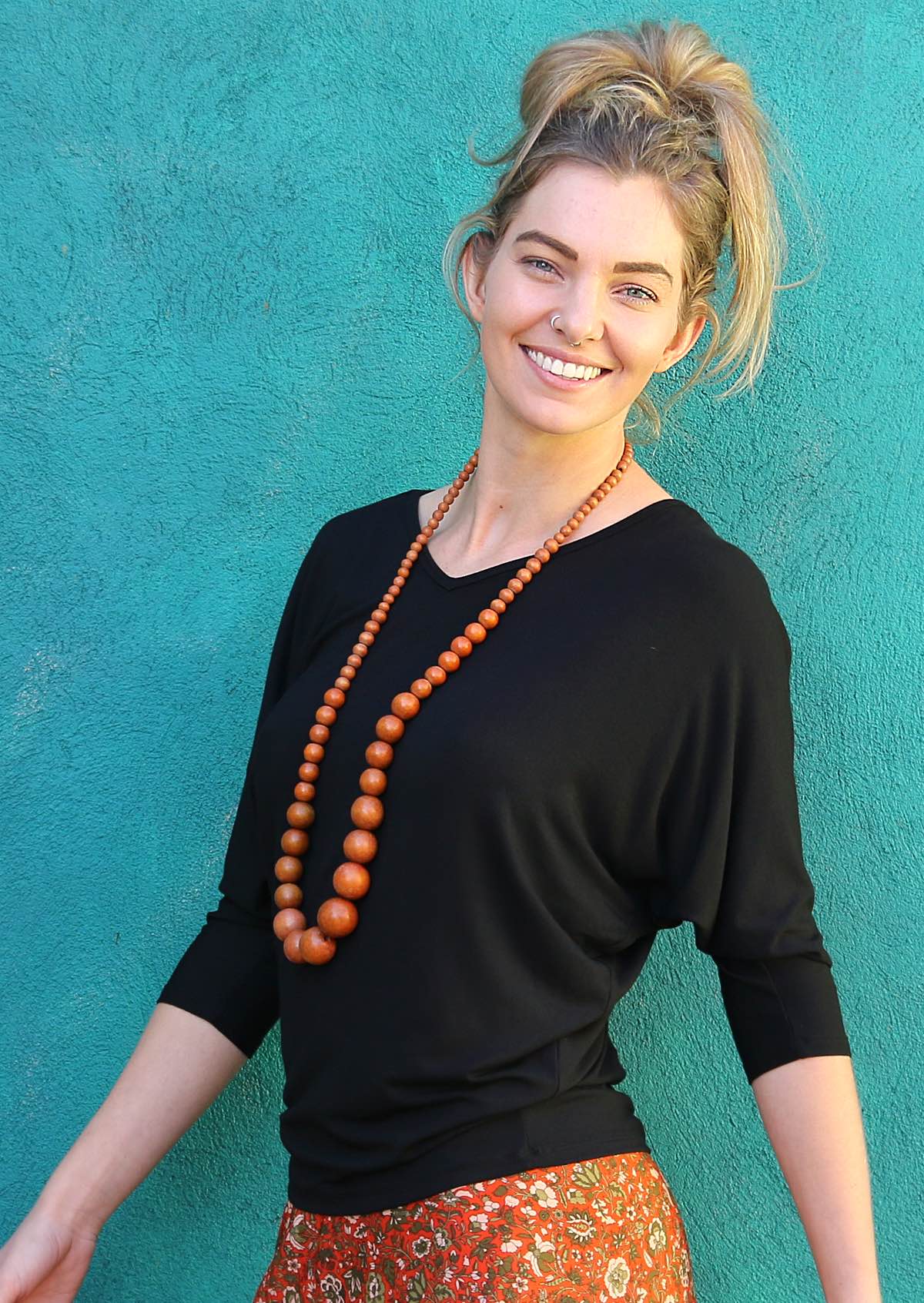 Woman with nose ring wearing a 3/4 sleeve rayon batwing v-neck black top.