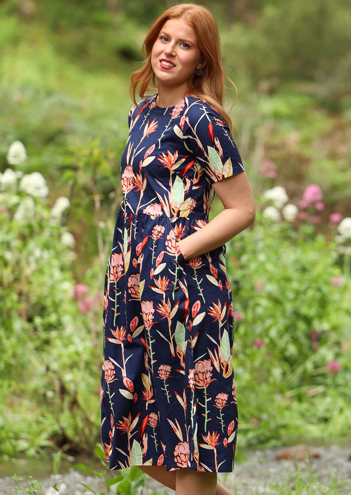 Woman wearing midi dress with large side pockets and a gathered pleat waist detail