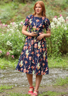 Woman wearing below the knee length cotton midi dress with navy background native floral print