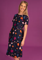 Model posing in loose fit short sleeve dress with pockets and high round neckine.