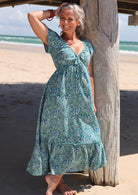 Model wearing 100 percent cotton maxi dress with elasticised cross-over bodice and tier at the bottom of the dress.