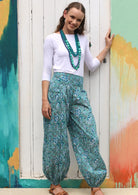 Woman wears cotton boho style pants in aqua and white floral print.