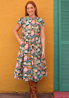 Model wears 100% cotton button through  dress with pin tuck pleats at front panel leading into the skirt.