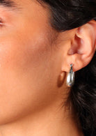 Close up of sterling silver hollow tapered hoop earring with hinged clasp