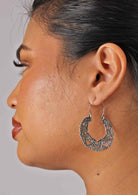 Woman wears lace mandala silver earrings that measure 41mm wide and 52mm long including the wire hooks