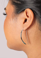 Woman wears fixed hook sterling silver earrings with curved shape