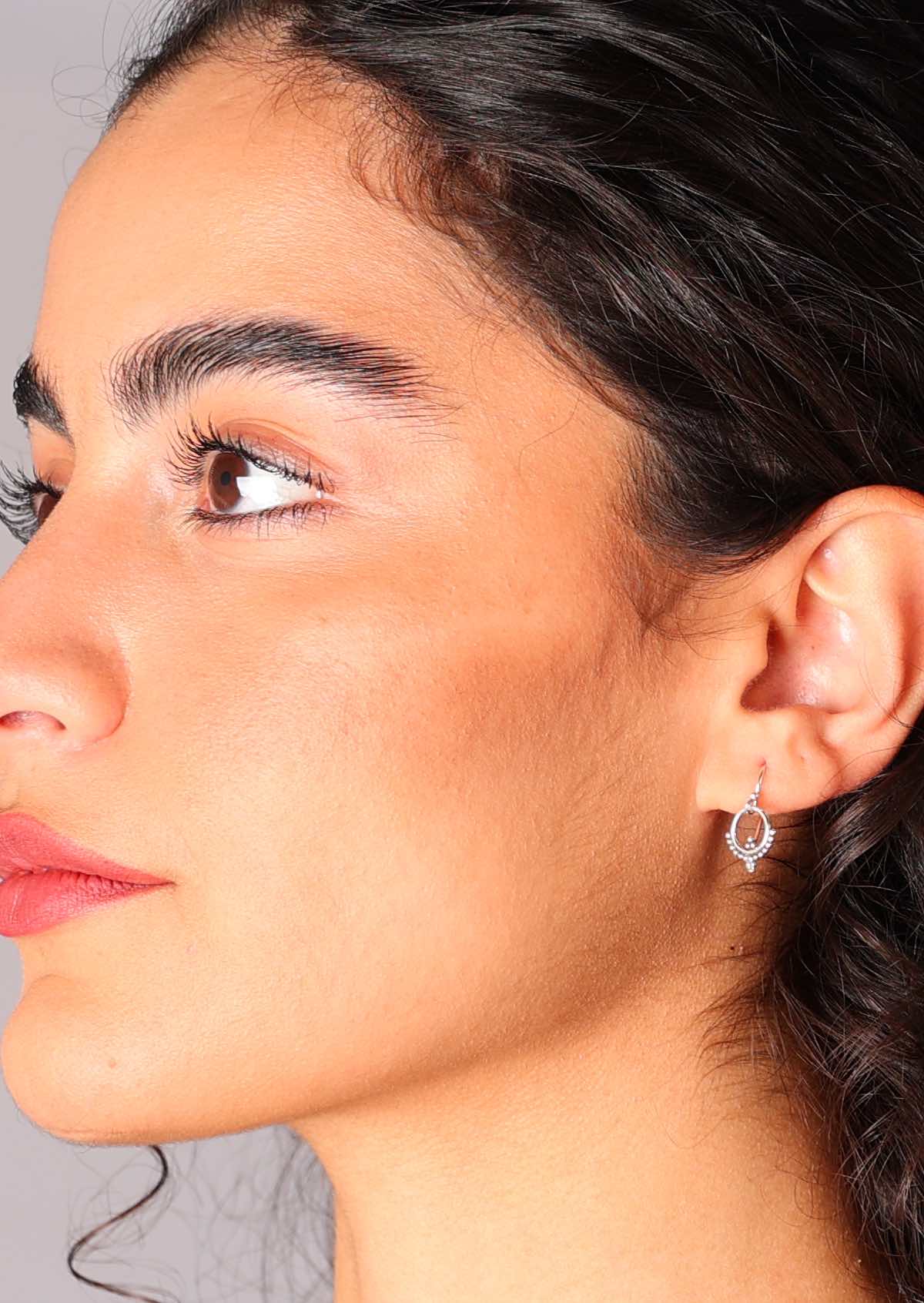 Woman wears small sterling silver ring suspended from an earring hook