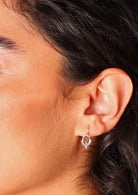 Close up of woman wearing small sterling silver ring suspended from an earring hook