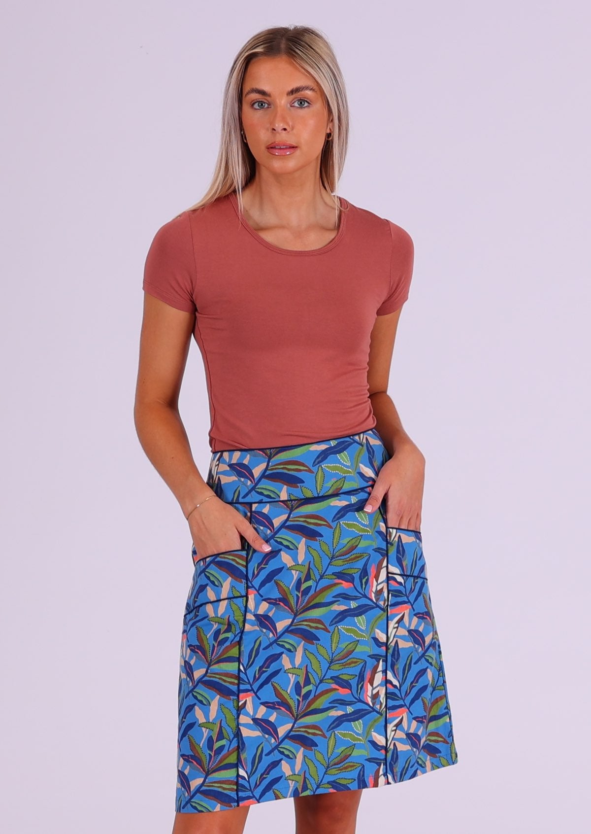 Model wears blue based leafy print cotton skirt with hands in pockets, paired with a stretch rayon top in dusty pink