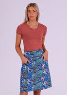 Model wears blue based leafy print cotton skirt with hands in pockets, paired with a stretch rayon top in dusty pink